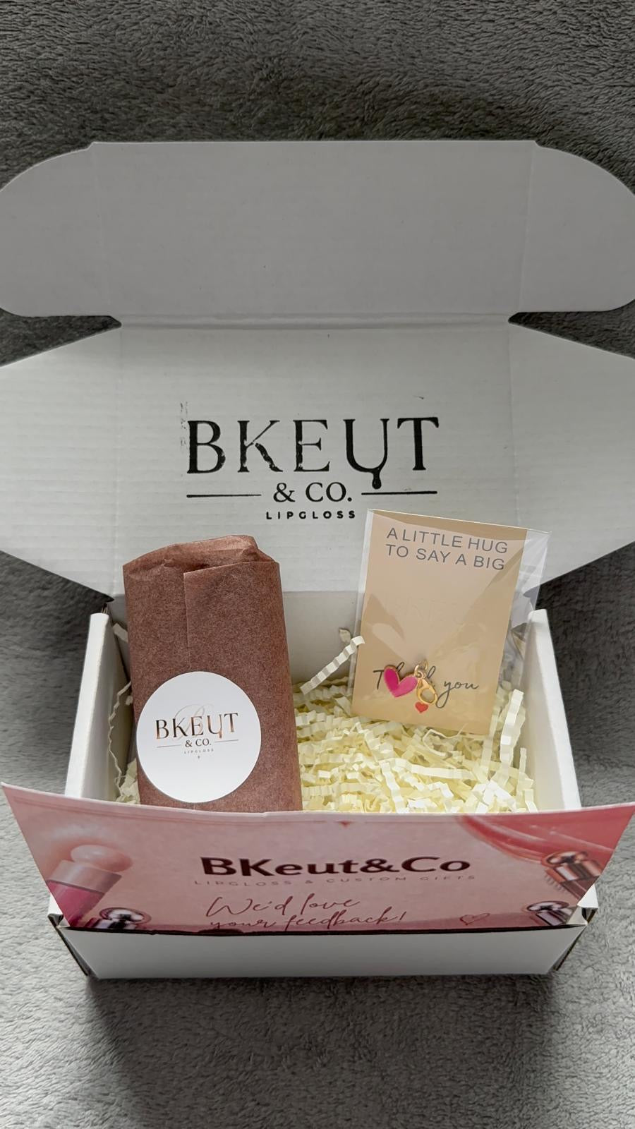 Open BKeut and Co gift box with wrapped lip gloss and thank-you card